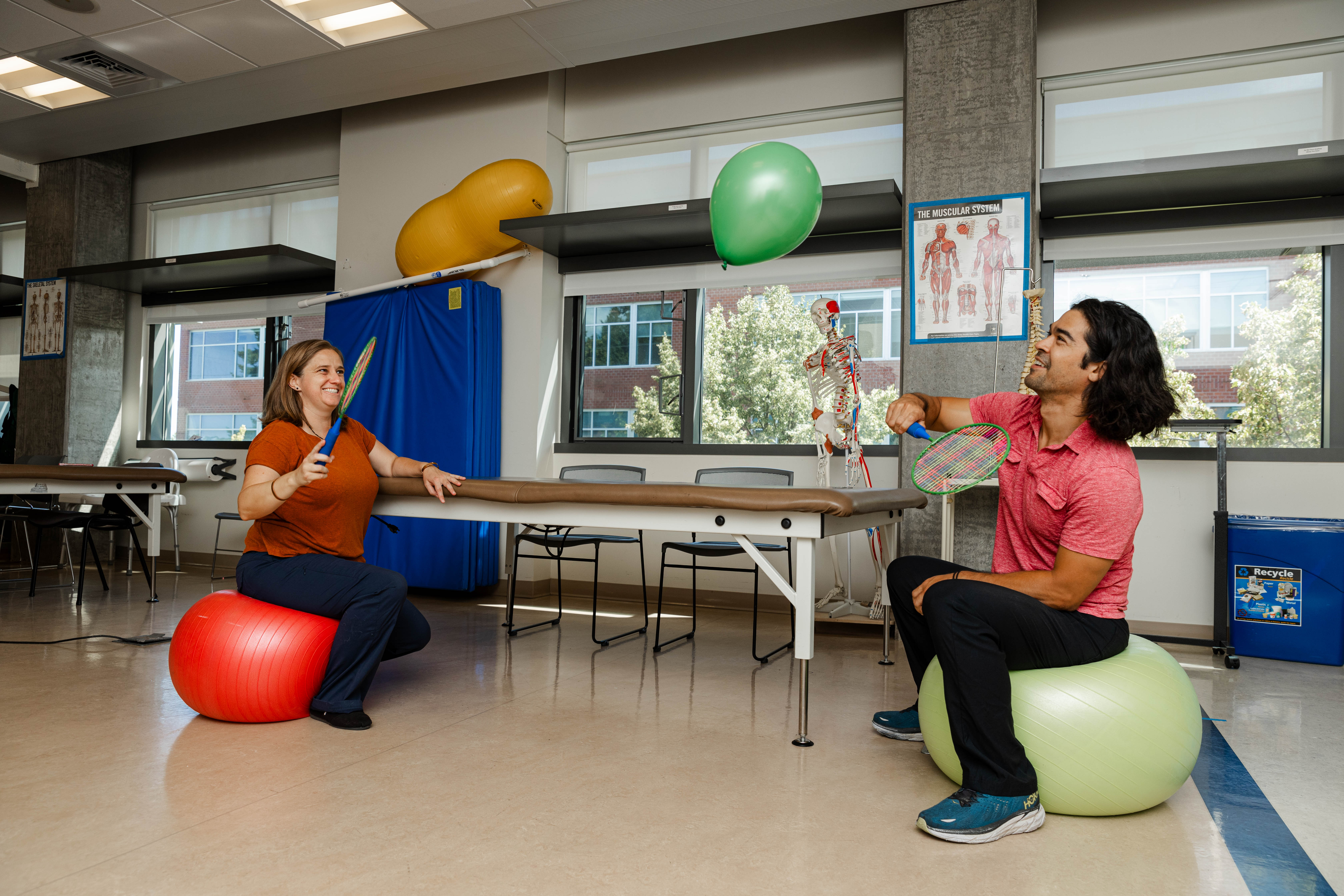 Two occupational therapy students demonstrate a common therapy exercise using balloons.