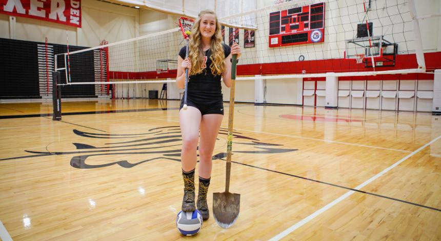 Hannah Hulse on the volleyball field with her firefighting gear