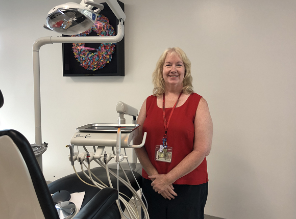 Dental Hygiene Studies founding director Lisa Rowley stands in program's clinic next to a dental chair