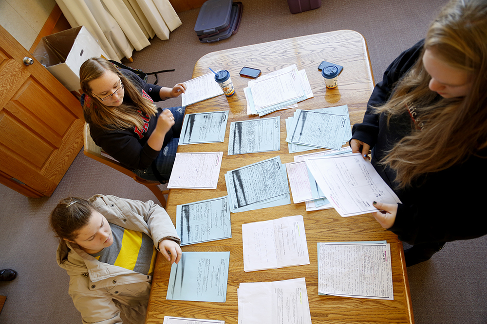 Students studying at table full of papers