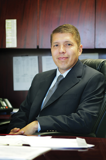 Manuel Castaneda seated at his desk in the office. 