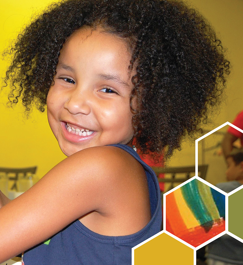 Jada smiling in front of a yellow wall. 