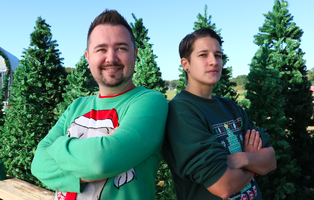Brittany Hartmann '12, MAT '15 and Jordan Slavish stand, arms crossed, in front of evergreen trees