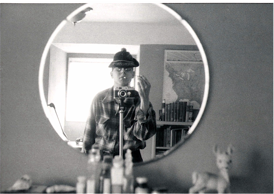 black and white photo of a man looking in a mirror