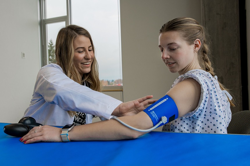 Julia Senestaro (Left) Practices Taking A Blood Pressure Reading With Shelby Gregg