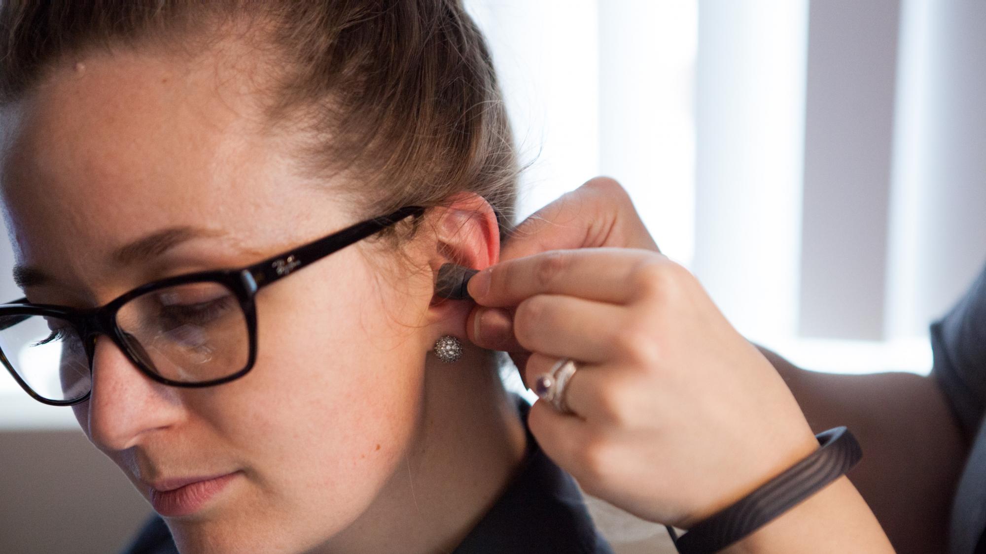 Girl wearing glasses getting her hearing examined.