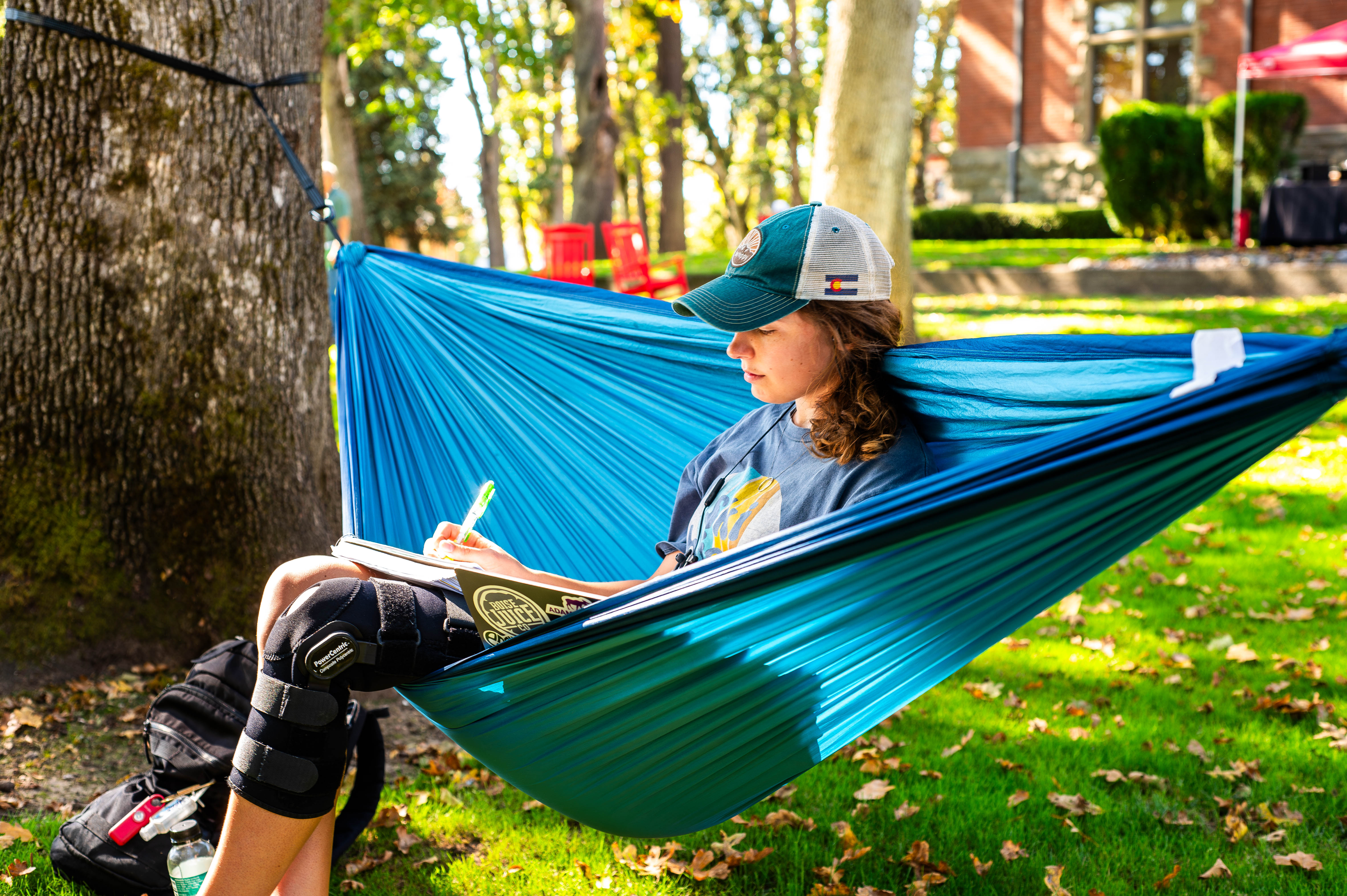 Pacific University student Brynn Barber studies outside while sitting in a blue hammock.
