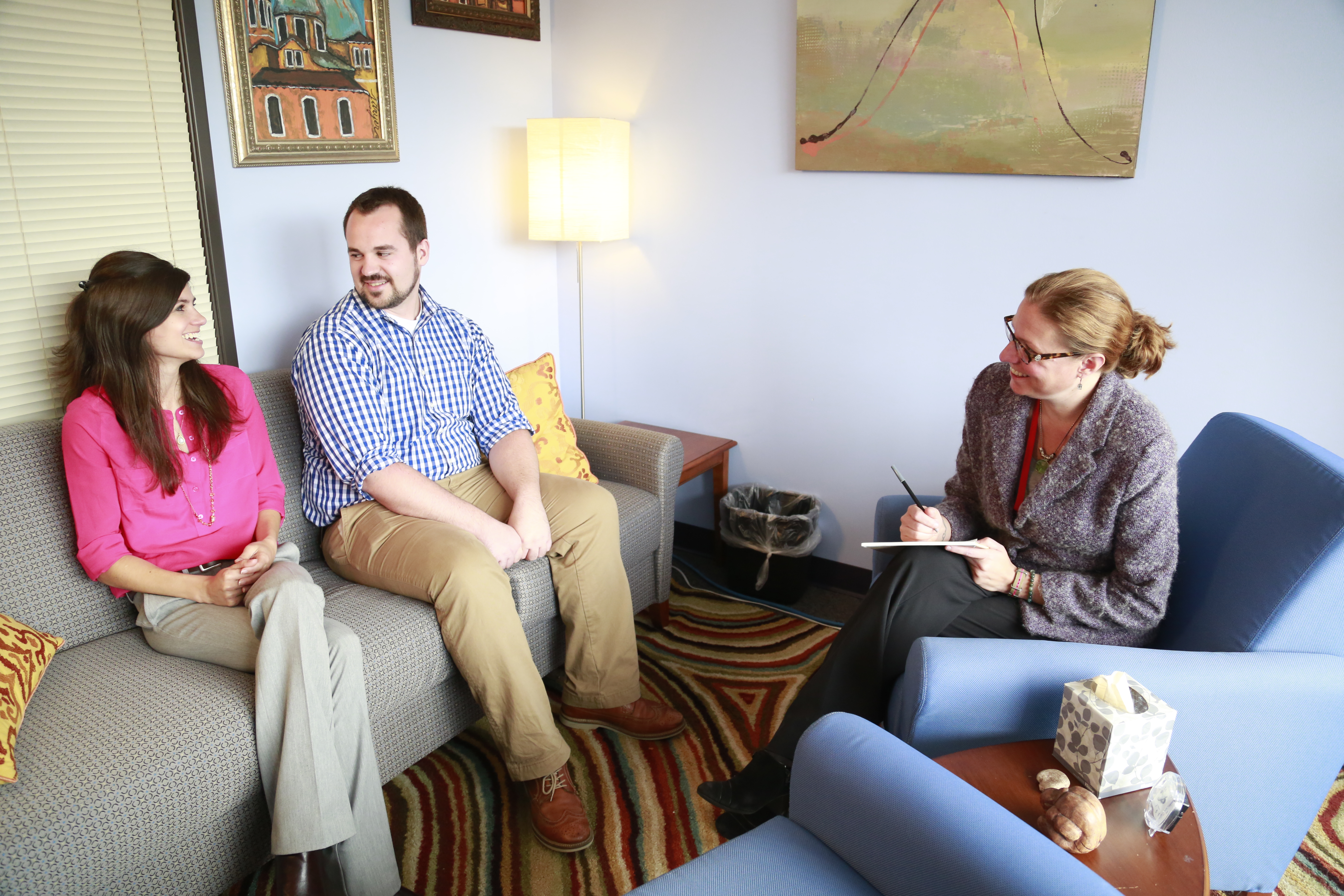 A clinical psychologist leads a therapy session for a young couple.