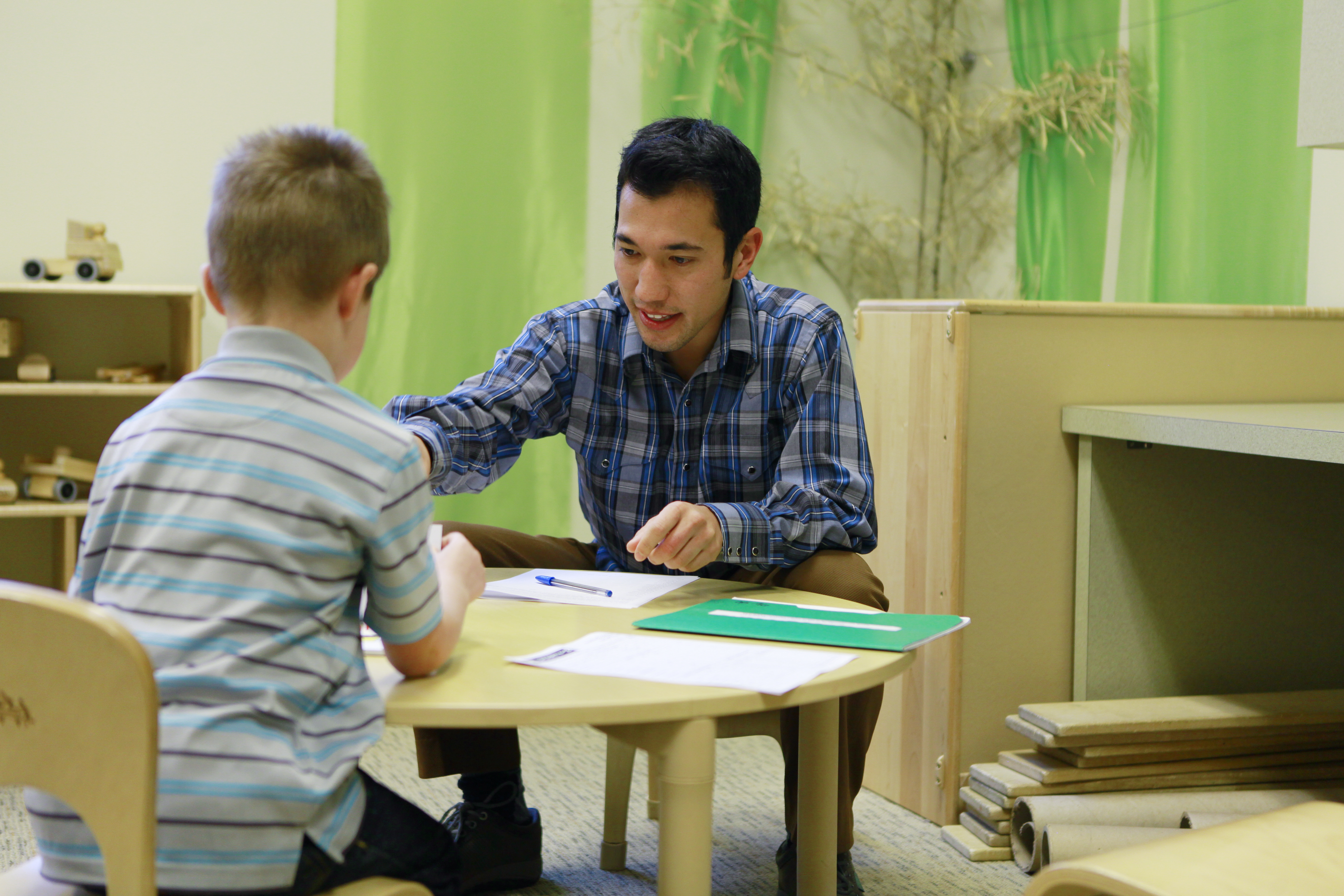 A speech-language pathology student works with a young child in a pediatric clinical setting.