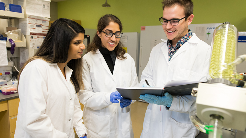 Pharmacy students examine an experiment in the pharmacy lab with a faculty member