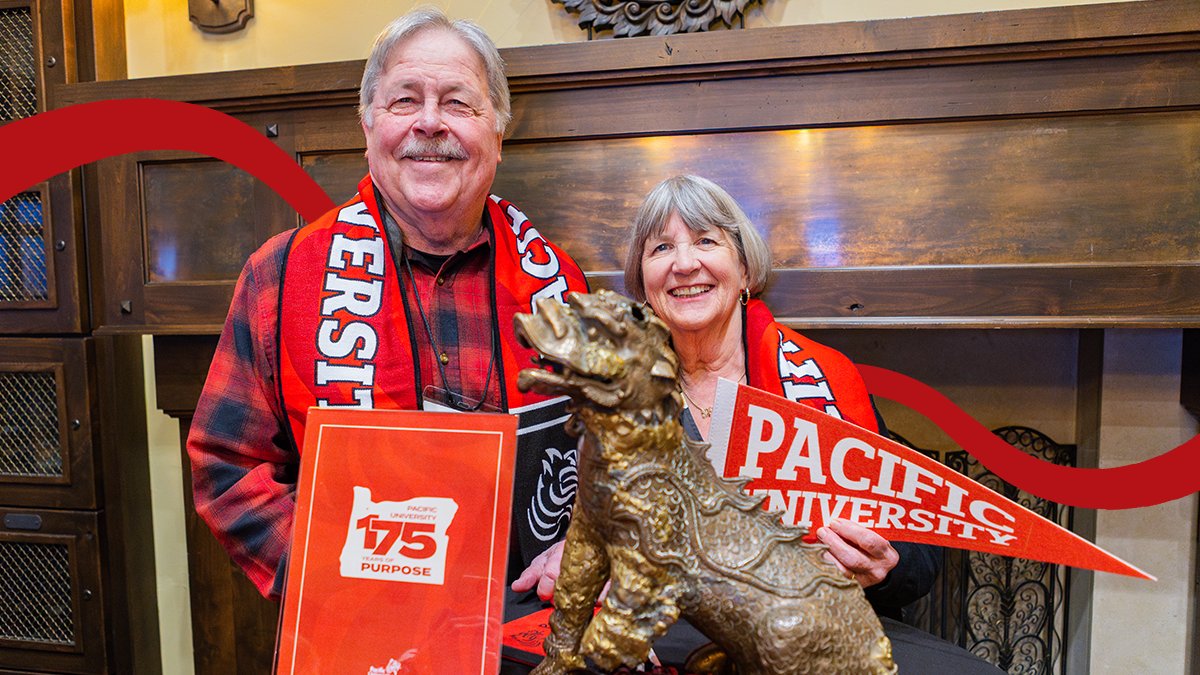 A couple wearing Pacific University scarves pose with the original Boxer statue and a red pennant reading "Pacific University" at a 175th anniversary event.