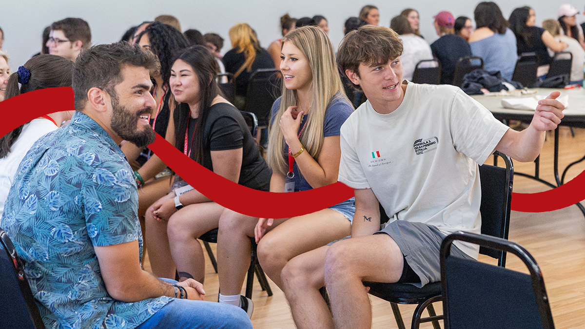 A group of college students sit in facing rows during an icebreaker activities for transfer students.