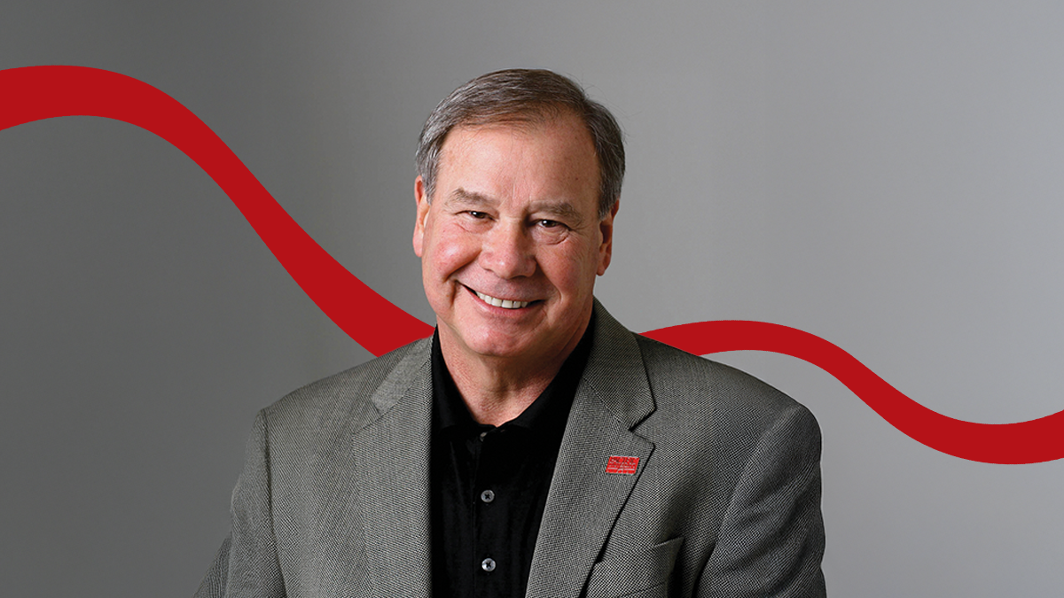 A portrait of Pacific University President Emeritus Phil Creighton wearing a black shirt, gray suit jacket, and red Pacific lapel pin.