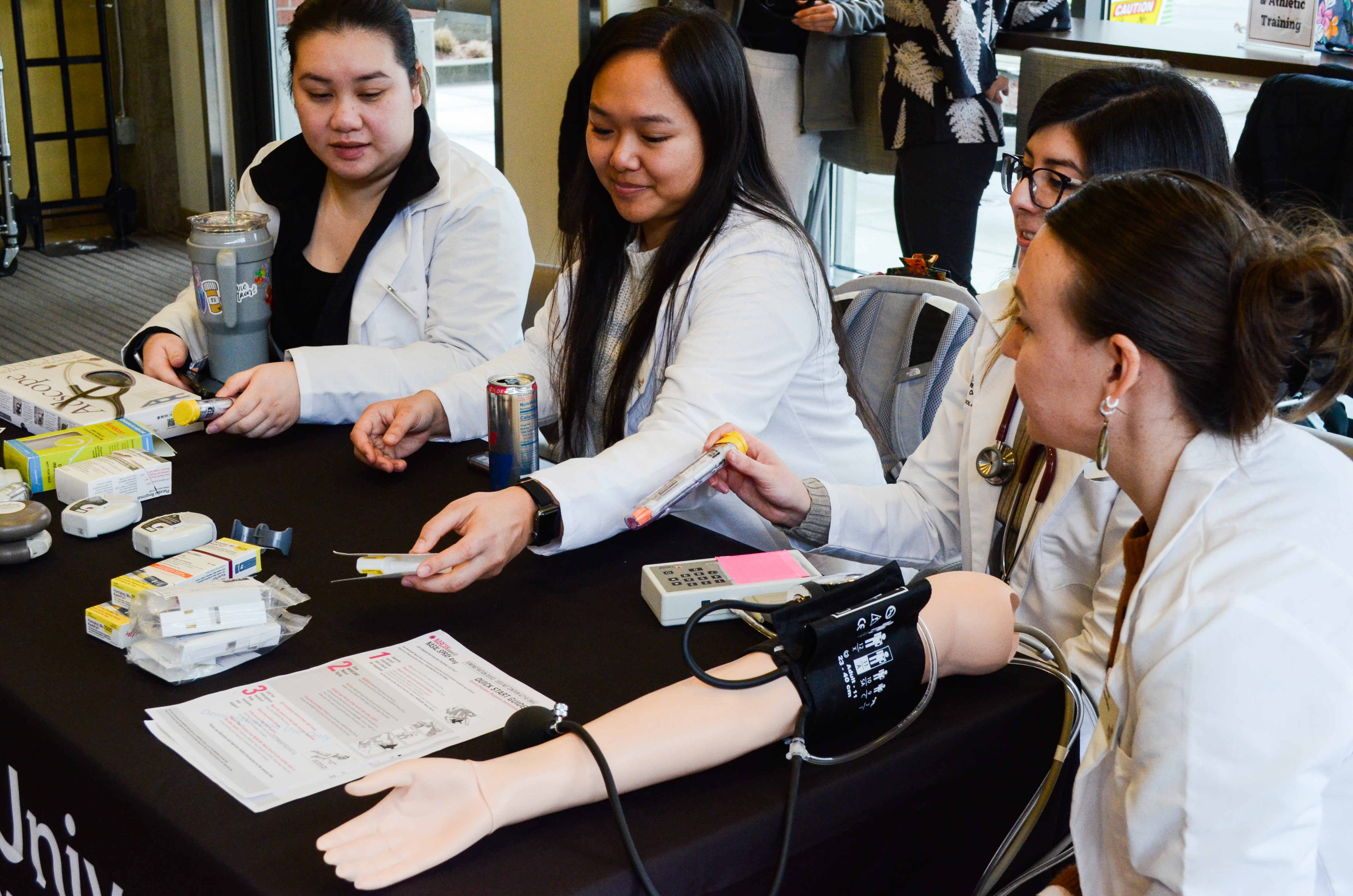 Blood pressure measurement demonstration during poster presentations at the Caring Through Discovery healthcare showcase at the Pacific University Hillsboro Campus.
