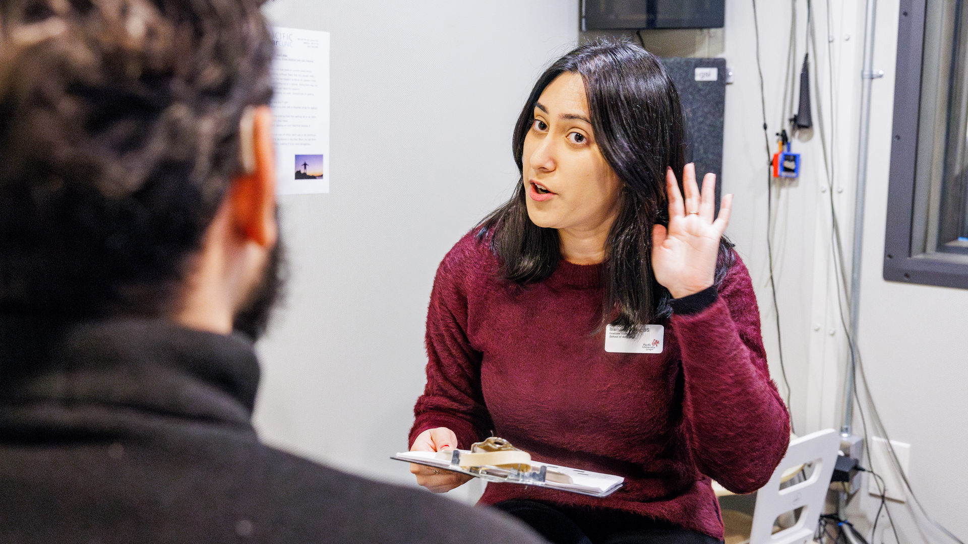 An EarClinic staffer holds her hand to her hear while communicating with a patient.
