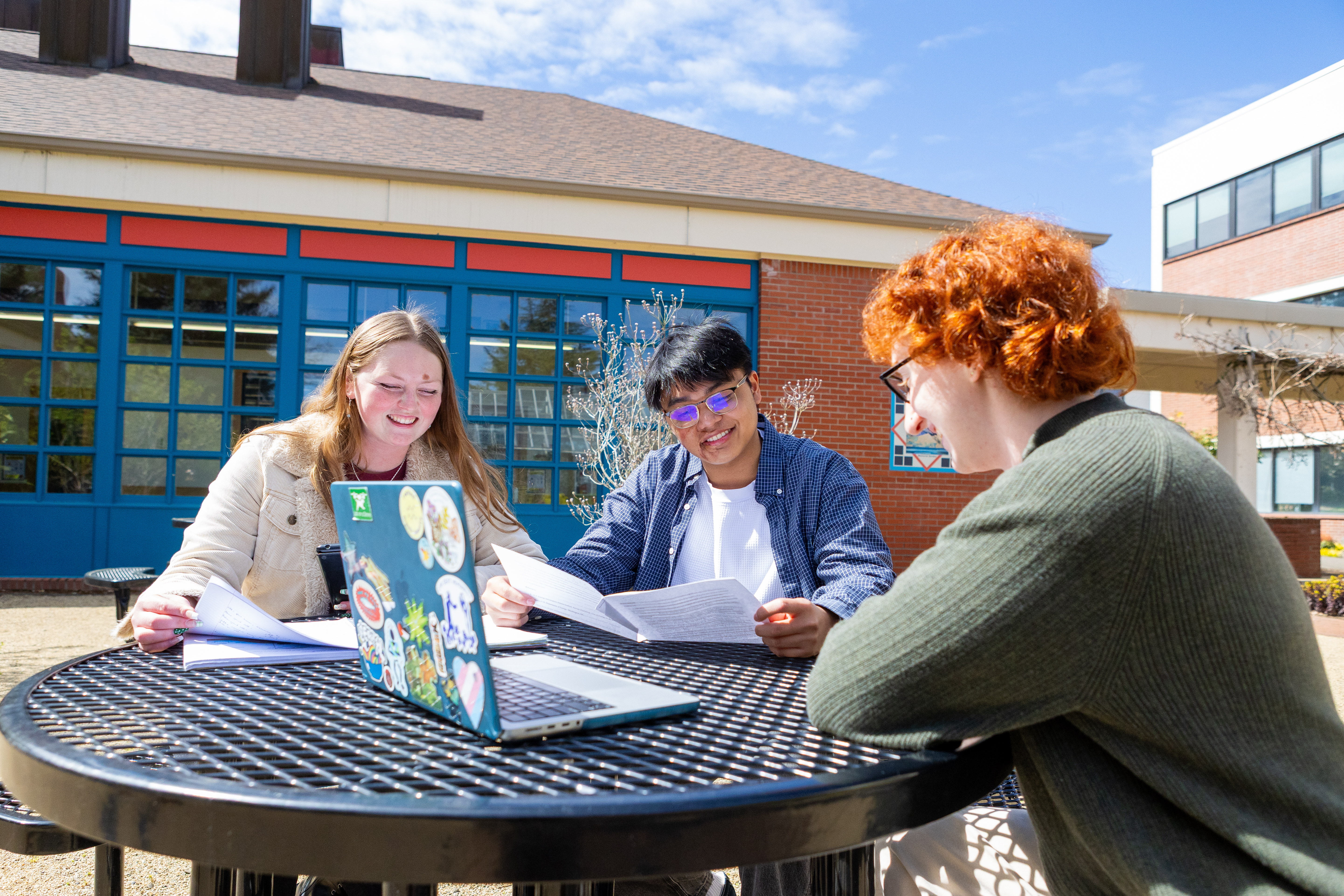 Three Pacific University students studying around a table outside on a sunny day