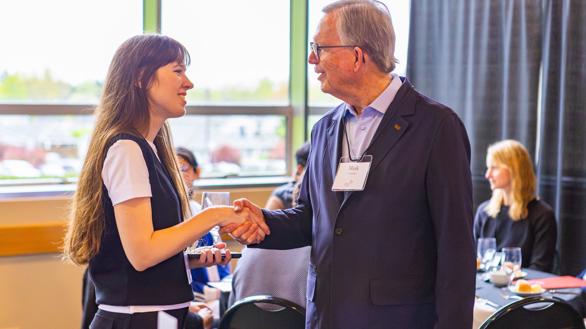 A student scholarship recipient shakes hands with a member of Pacific's Board of Trustees