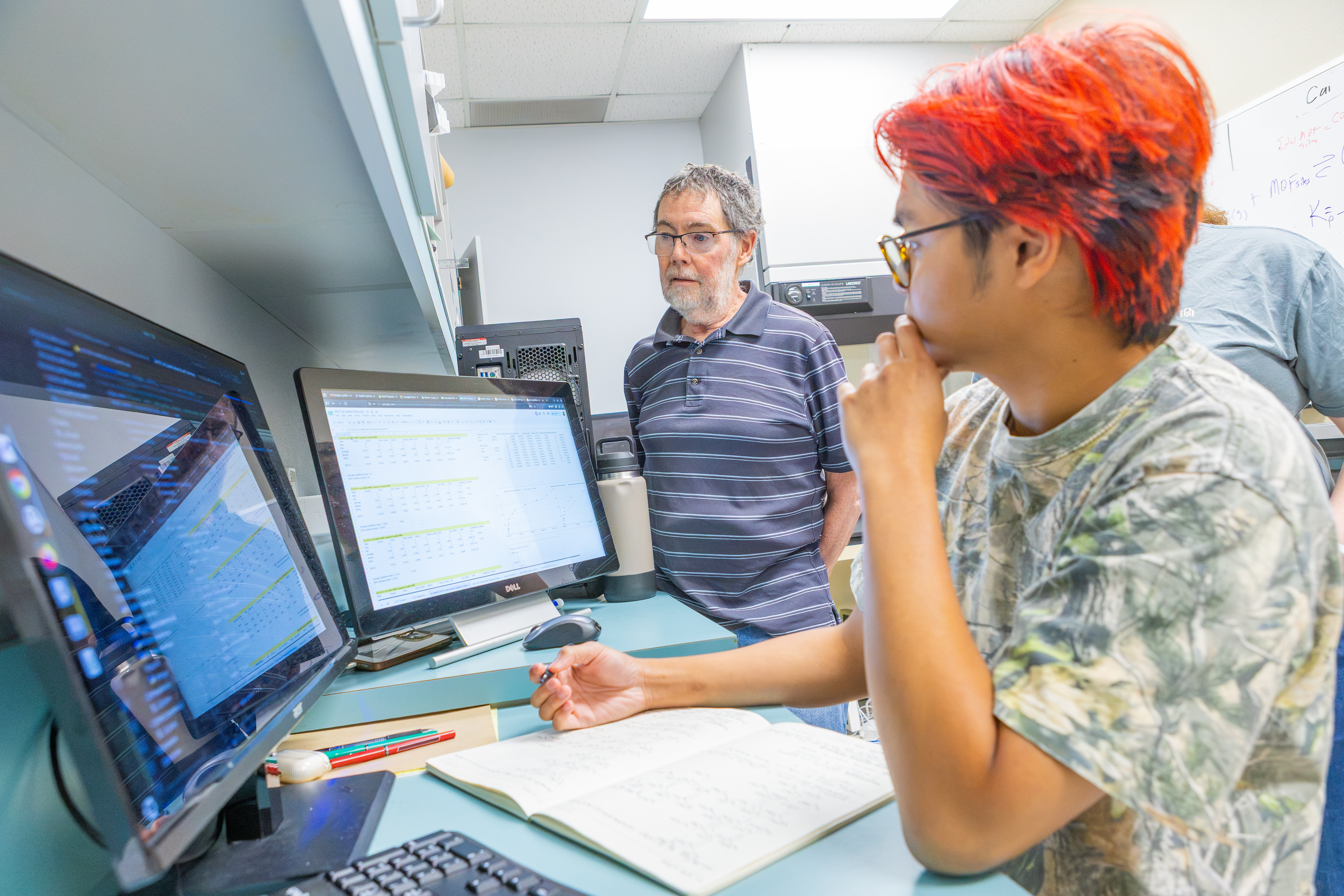 Pacific student with professor working on two monitors in computer lab