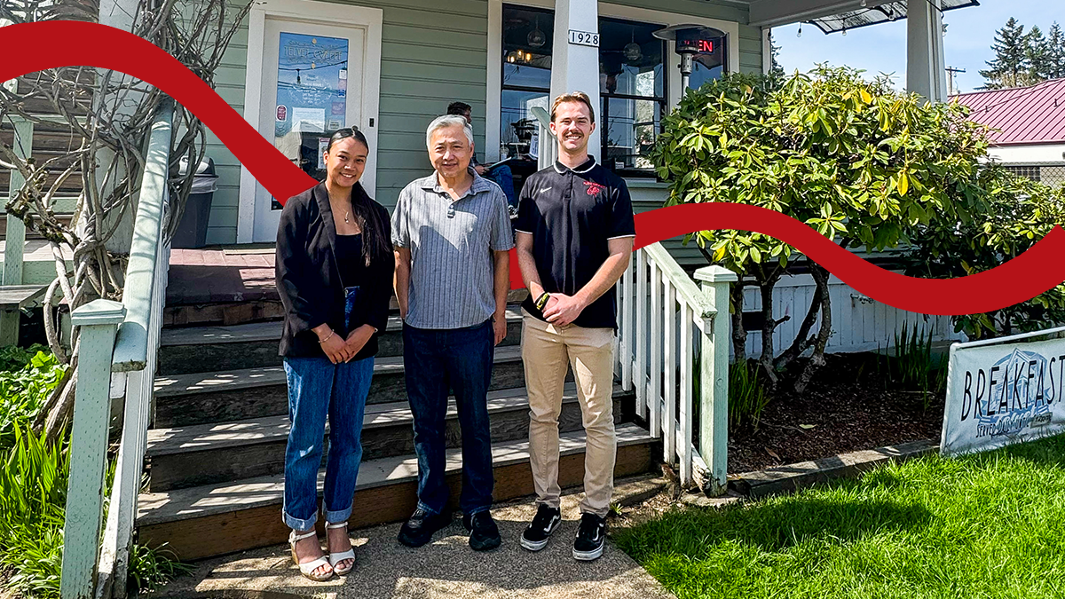 Pacific University business students stand on either side of the owner of Telvet Coffee, in front of his shop.