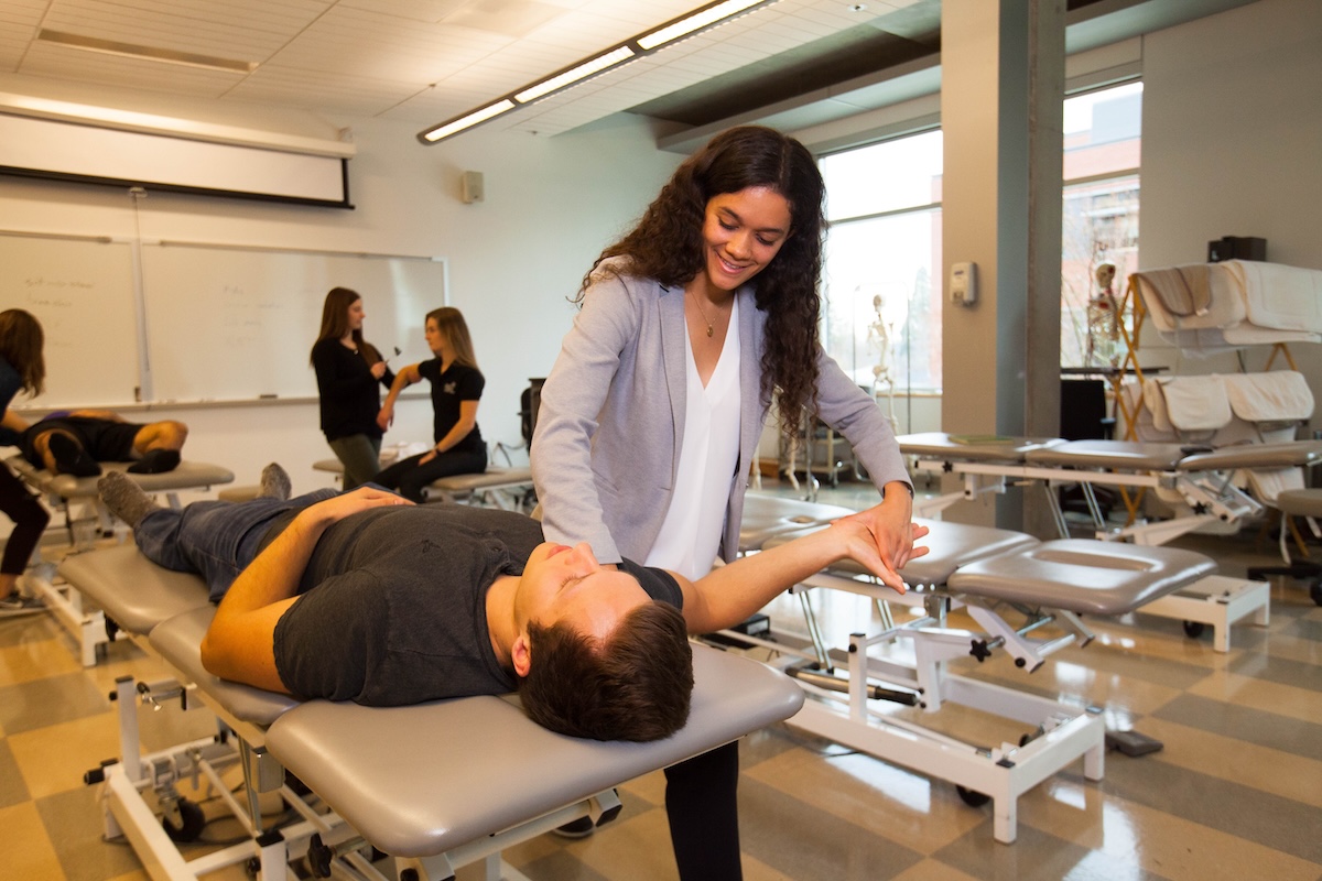 Two students demonstrate a physical therapy technique designed to increase shoulder mobility.
