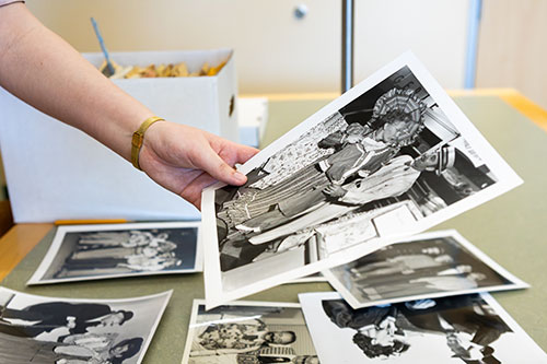 Hand holding a photo above table full of historic photos.