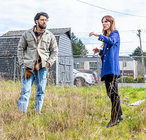 Brandon Dieckman and Hannah Studer in a discussion outside in front of a gray barn-shaped storage building.