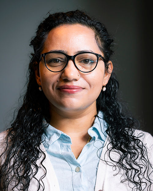 Headshot of Pabita Dhungel MS '19, a woman with long black hair. She is wearing black framed glasses, a blue blouse and a white sweater.