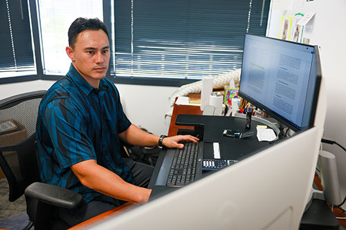 T.C. Campbell '14 at his desk at Pioneer Design Group - Hawai'i's offices in Honolulu.