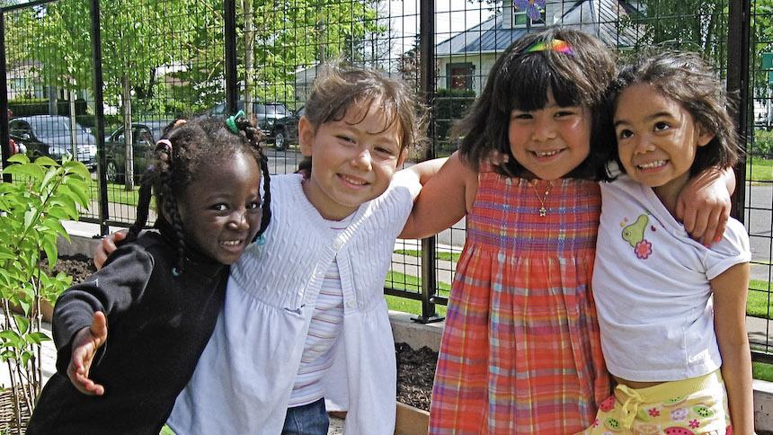 Children huddling for picture together outside in the sunshine.