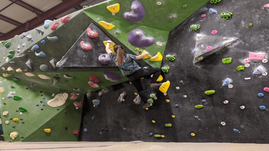 A climber scales a wall at an indoor climbing gym