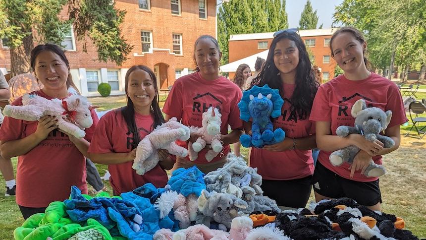 5 RHA members in red shirts hold a stuffed animal from the Fuzzy Friends event