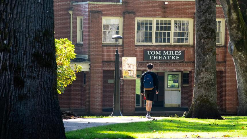 A student walks through Pacific University's Forest Grove Campus toward Tom Miles Theater