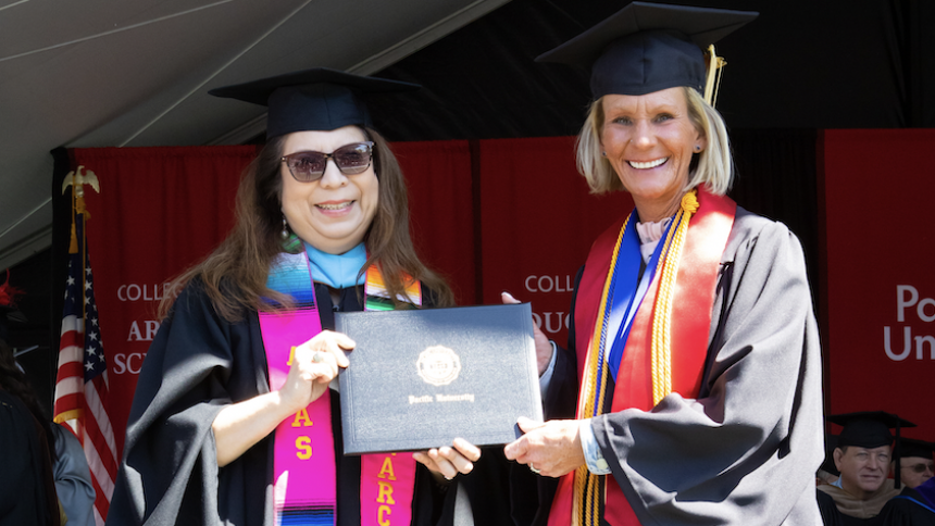 Wendy Fargo receives a Pacific University diploma on stage with Narce Rodriguez