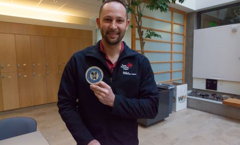 Mark Loomis OTD '17 holds up his rescue swimmer patch at the Hillsboro Campus