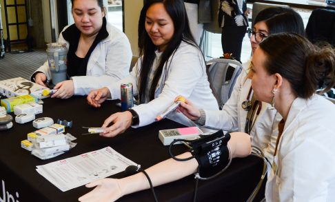 Blood pressure measurement demonstration during poster presentations at the Caring Through Discovery healthcare showcase at the Pacific University Hillsboro Campus.