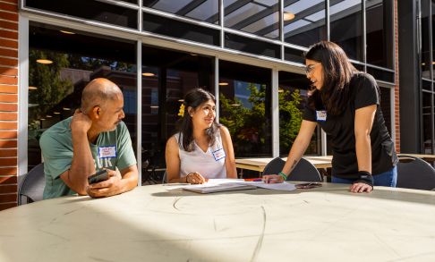 Pacific University students and advisors meeting at a table outside a campus building