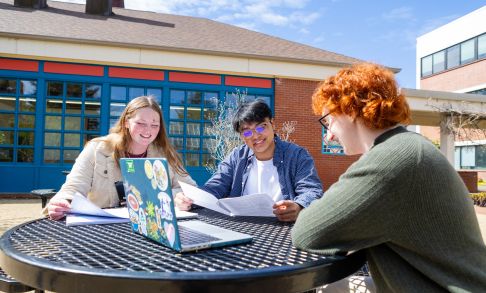Three Pacific University students studying around a table outside on a sunny day