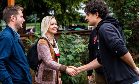 A current Pacific undergraduate students greets two alumni during Homecoming weekend.