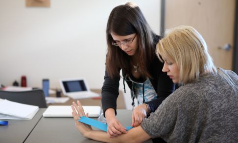 An occupational therapy student assists a patient using a resistance band.