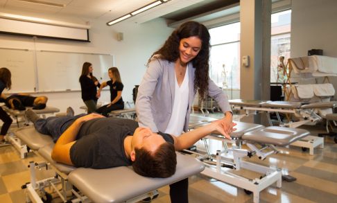 Two students demonstrate a physical therapy technique designed to increase shoulder mobility.