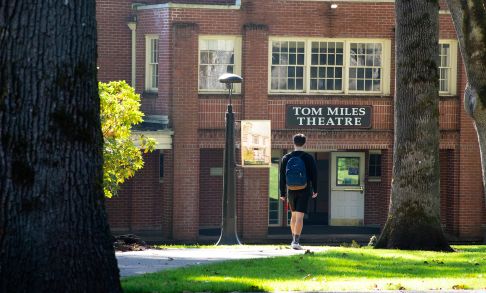 A student walks through Pacific University's Forest Grove Campus toward Tom Miles Theater.