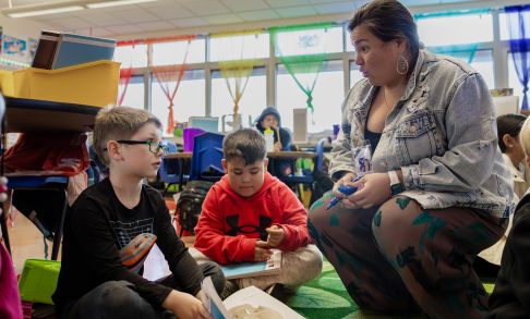 A student teacher helps an elementary school student in a classroom setting.