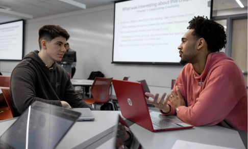 Two students discuss a question during class.