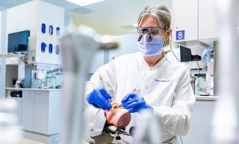 Amy Coplen practices dental techniques on a model of a human mouth.