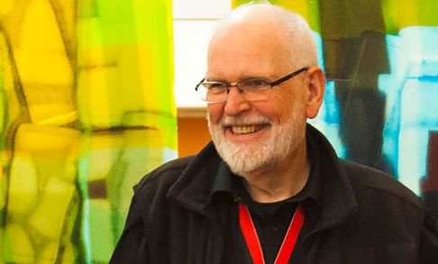 Bruce Bishop '68 stands in front of the Tran Library's multi-color panels.