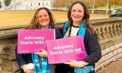 Kerry Mandulak And Jordan Tinsley Holding "I Am An Advocate" Signs