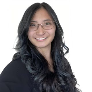Headshot of Melissa Gabel, She Chinese. Her hair is dark brown with blue highlights. She is smiling and wearing glasses and black shirt with a white background.