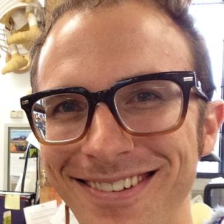 photo of Casey Miller, smiling and wearing glasses