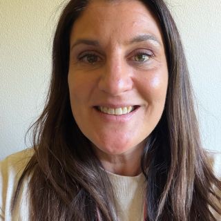 Female with long, straight, brown hair with a plain background.