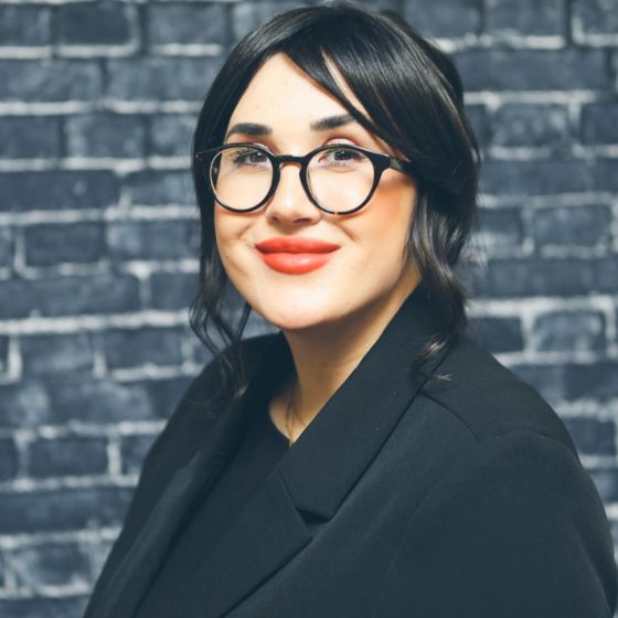 Image of Danielle Walker wearing black shirt, black jacket, black eyeglasses.